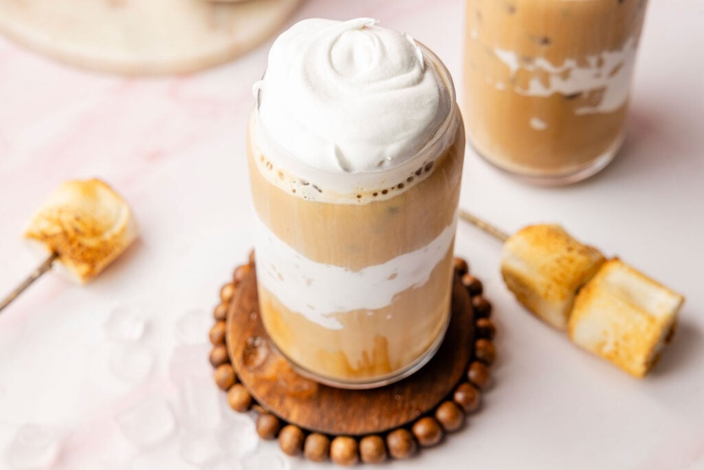 Marshmallow fluff lined cup for twisted marshmallow latte with marshmallows in the background