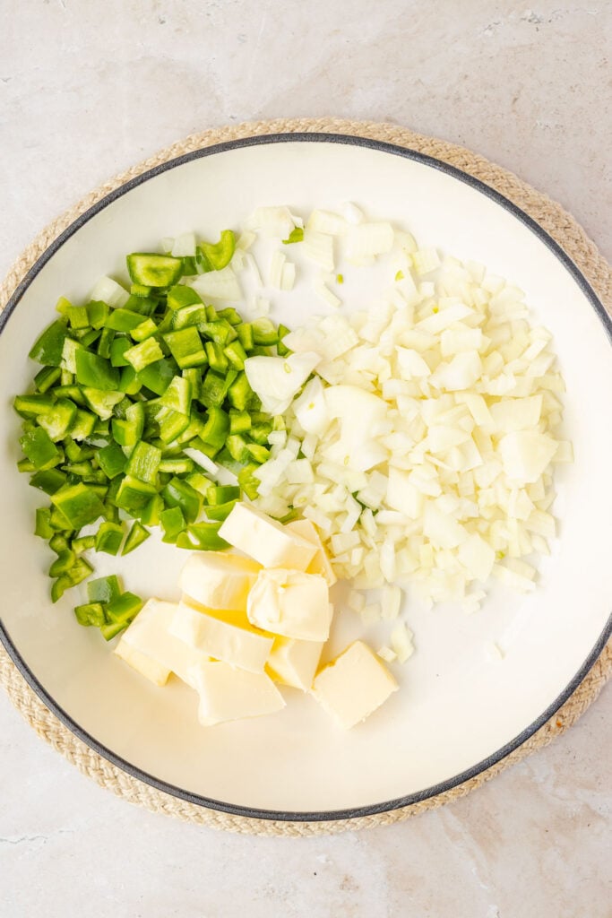 Butter with spices, onions, garlic, and green bell pepper in. a pan