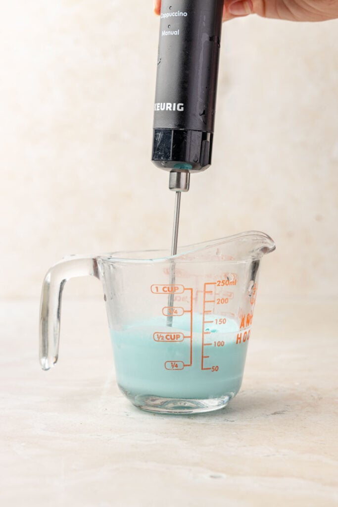 Whipping up a blue raspberry cold foam. In a measuring cup.