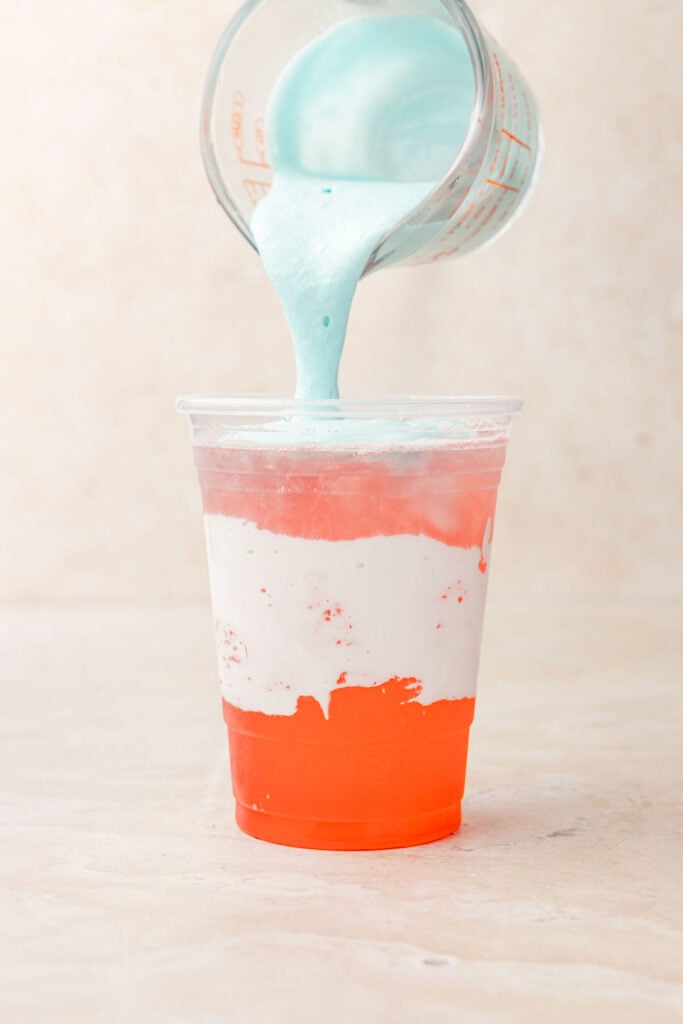 Pouring blue raspberry cold foam on top of dirty alani.