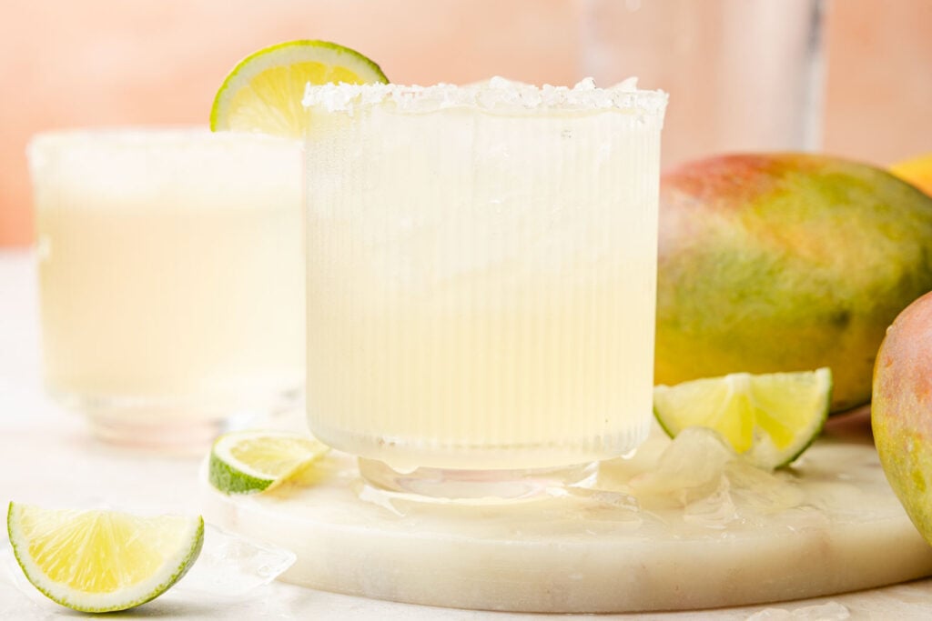 Mango Margarita with a lime on a piece of marble with mangos