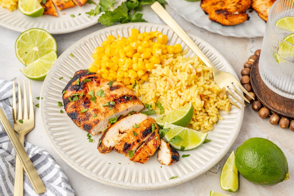 Tequila lime chicken on a plate with rice and limes