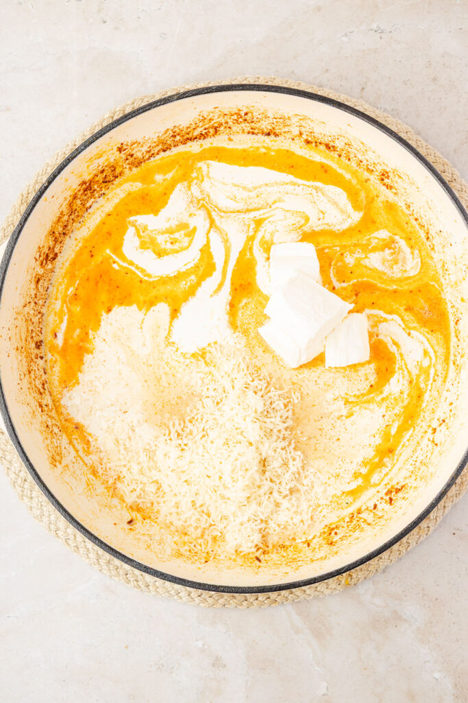 Heavy cream and Parmesan to make creamy garlic sauce in a pan.