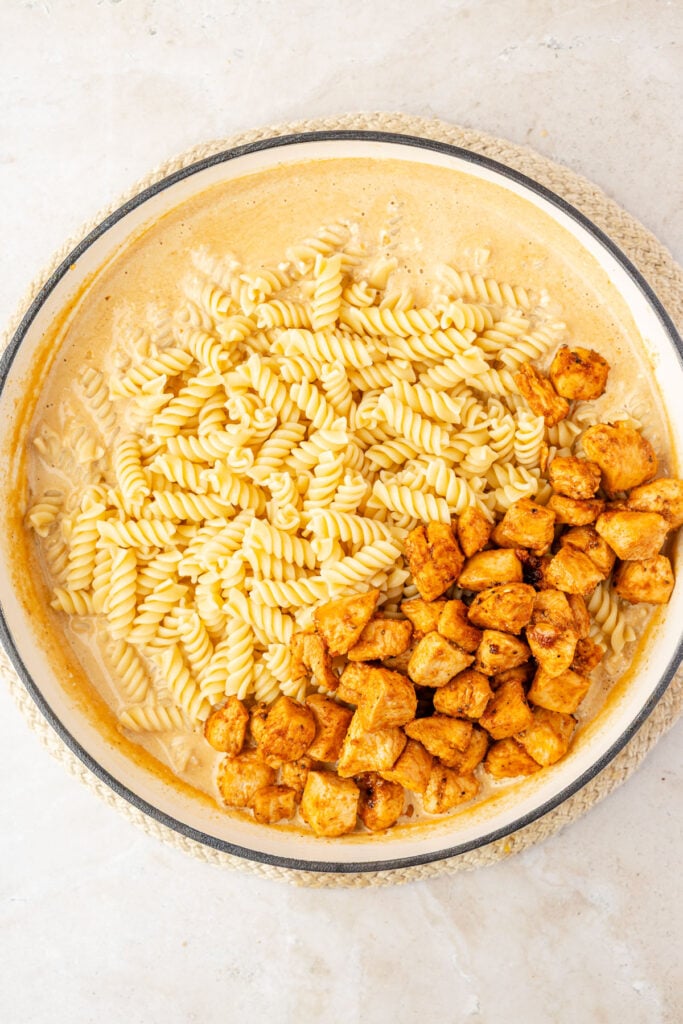 Creamy garlic sauce with pasta and chicken on top. In a pan.