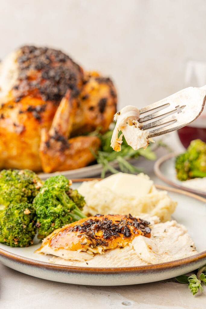 Herb Roasted Chicken cut on a plate with a fork holding up a piece.