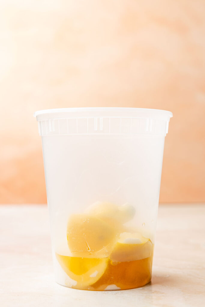 Container filled with lemons, sugar, and mango syrup.