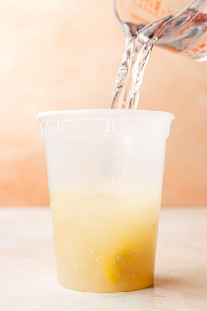 Water being mixed into the lemonade mixture in a container.
