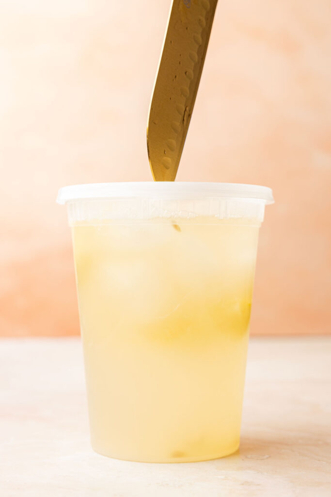 Piercing the container holding the mango lemonade.
