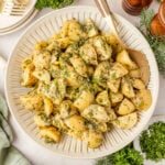 French Potato Salad (Easy No Mayo Potato Salad) in a bowl with herbs around it and a salt and pepper shaker.