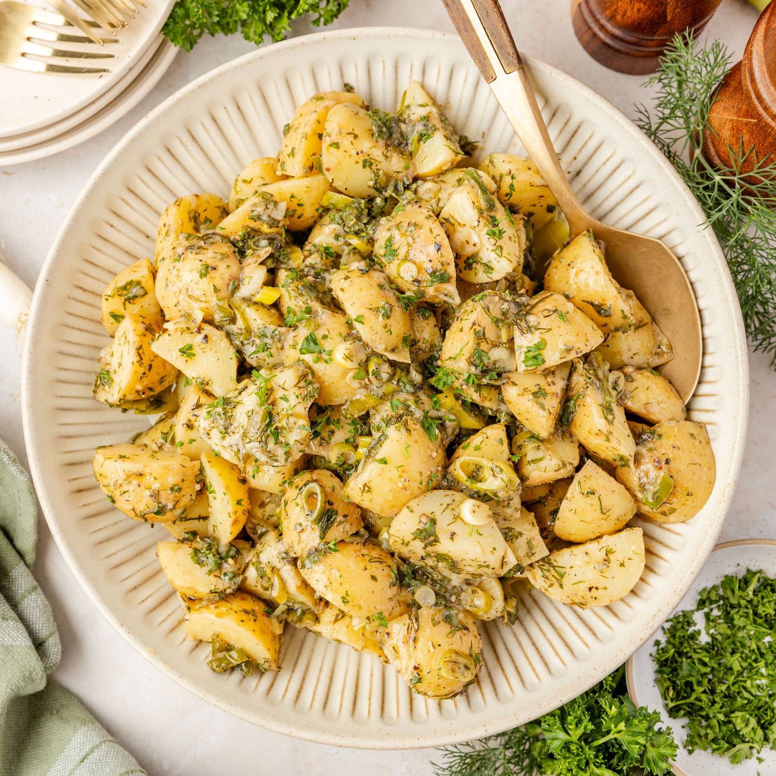 French Potato Salad (Easy No Mayo Potato Salad) in a bowl with herbs around it and a salt and pepper shaker.