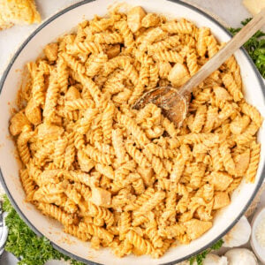 Creamy Chicken and Garlic Pasta in a pan wiht a wooden spoon