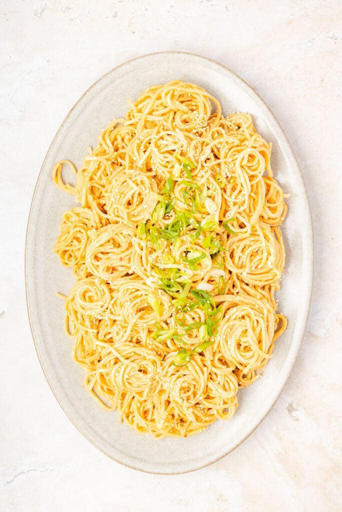 Sesame Noodles on a plate with scallions on top.