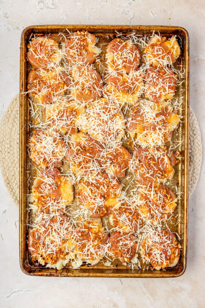 Mashed potatoes topped with Parmesan cheese on a sheet pan before going back in the oven