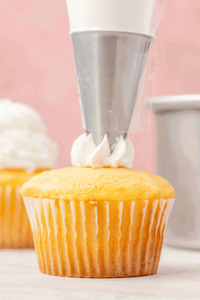 An animated of vanilla American buttercream bean piped onto a vanilla cupcake.