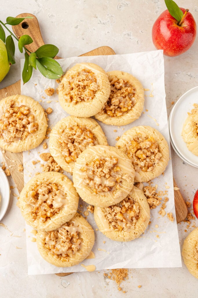 stack of Apple Pie Cookies on a cutting board with parchment paper and apples