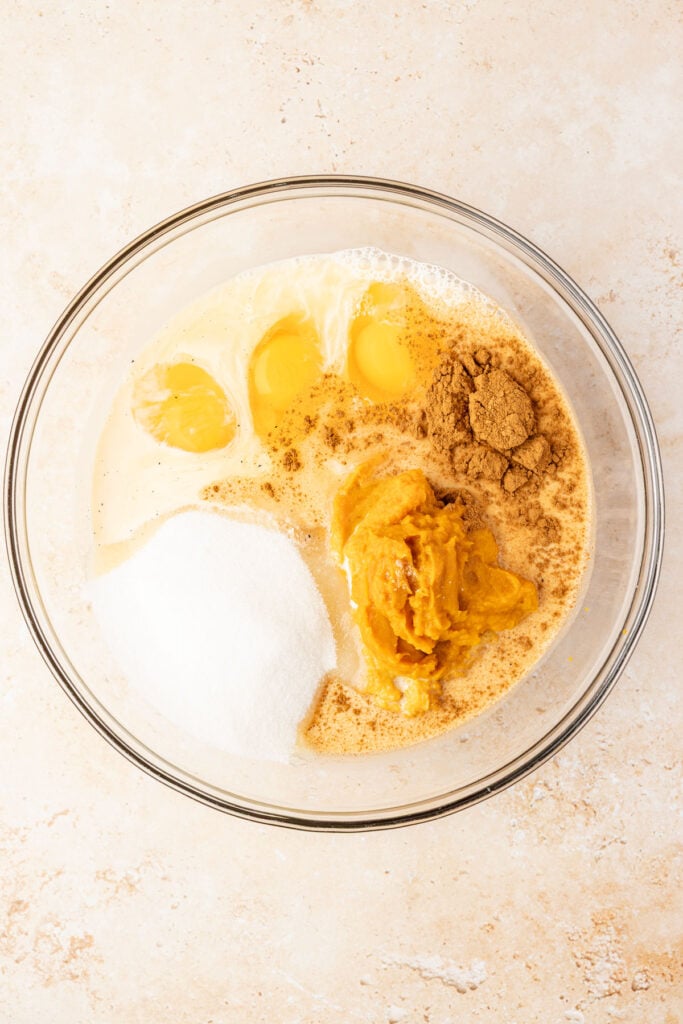 Mixing bowl filled with pumpkin purée, sugar, spices, eggs, evaporated milk