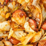 close up of Fried Cabbage and Sausage with a wooden spoon