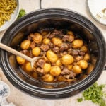 Slow Cooker Steak and Potatoes in a crockpot with a wooden spoon