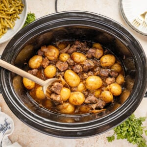 Slow Cooker Steak and Potatoes in a crockpot with a wooden spoon