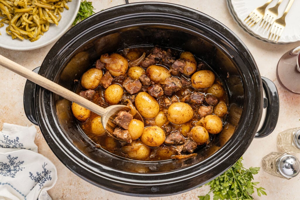 Slow Cooker Steak and Potatoes in a crockpot with a wooden spoon