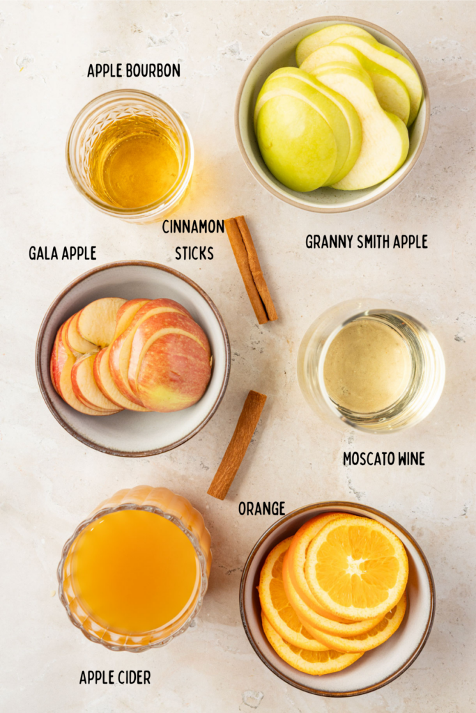 Ingredients for apple cider sangria in little bowls and cups.