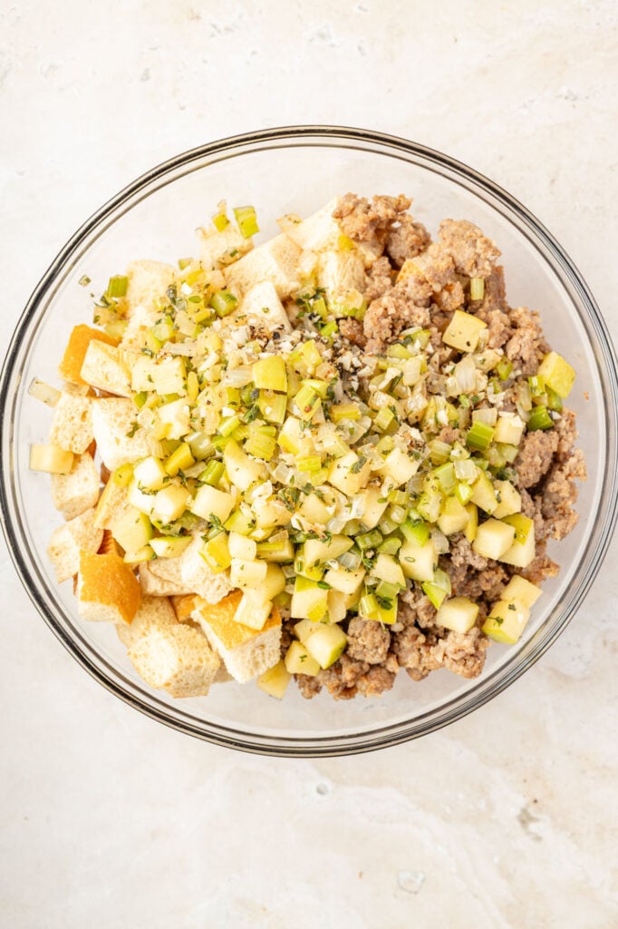 Bread, sausage, apples, sauce in a mixing bowl
