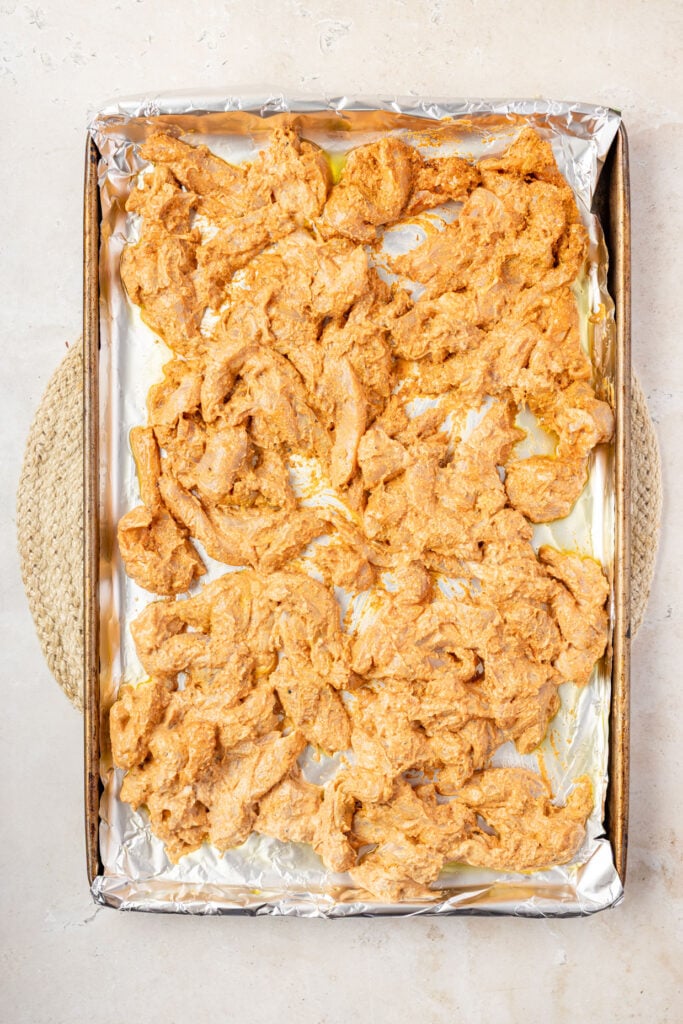 Raw marinated Shawarma chicken on a sheet pan.