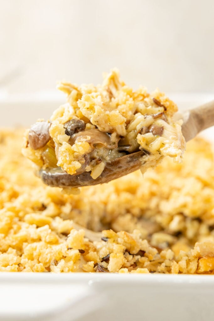 A wooden spoon scooping out a heating spoon of Chicken Wild Rice Casserole
