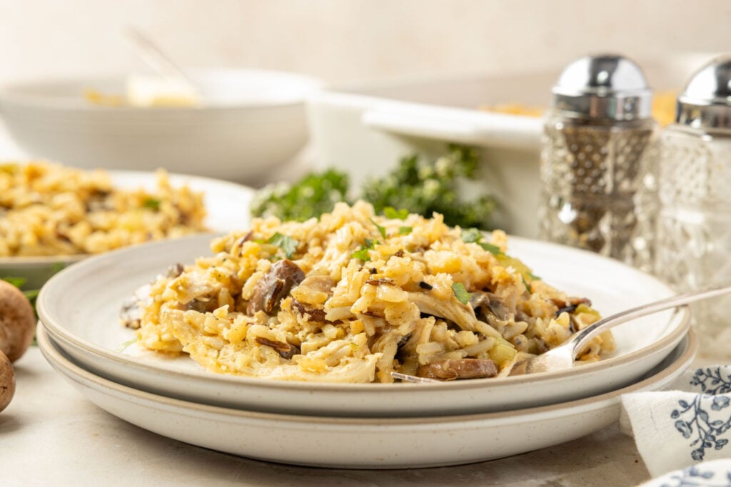 Chicken Wild Rice Casserole on a plate with the casserole pan and salt and pepper in the background.