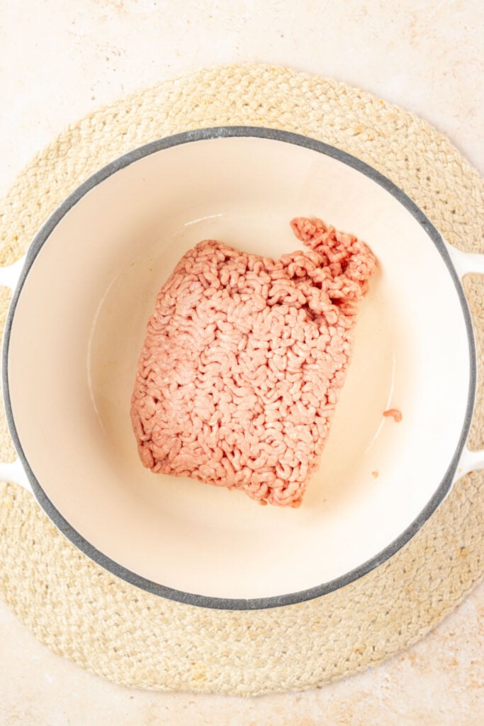 Raw ground beef in a Dutch oven for cowboy stew.