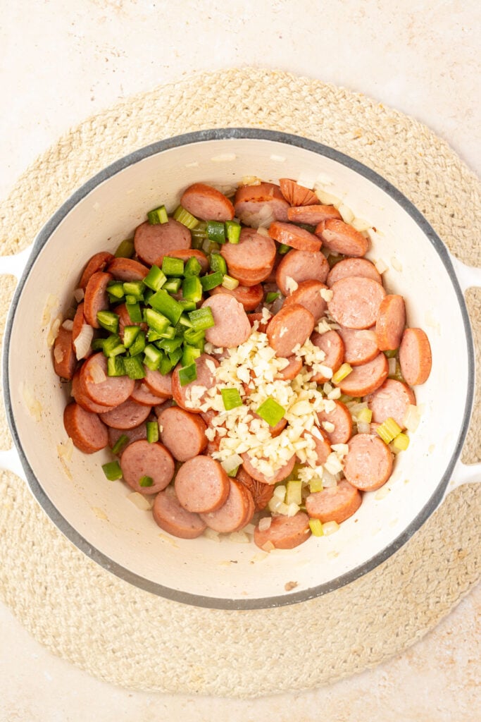 Cooked celery, onions, and raw sausage in the pot with jalapeños and garlic.