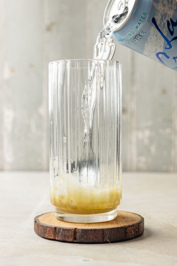 Pouring sparkling water over caramel mixture in a cup