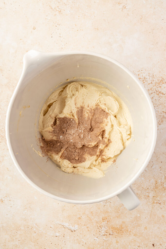 Creamed, butter and sugar with cocoa powder mixture being added in to mixing bowl.