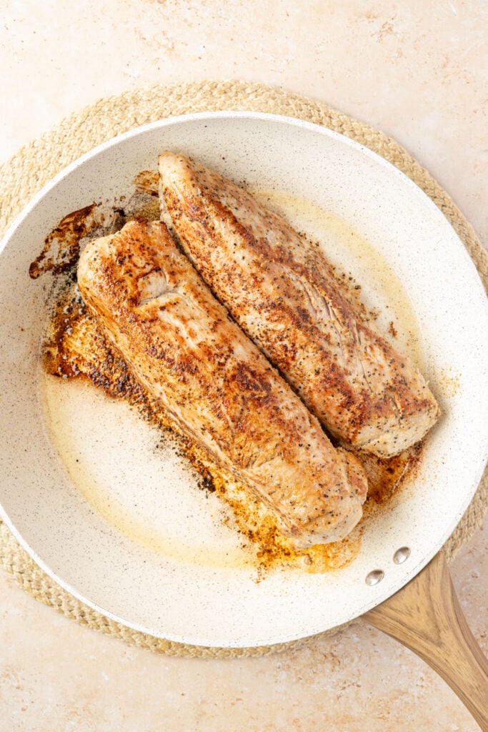 Seared pork tenderloin in a pan.