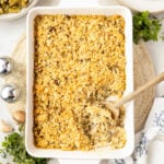 A casserole pan filled with Chicken Wild Rice Casserole and a spoonful taken out of it.