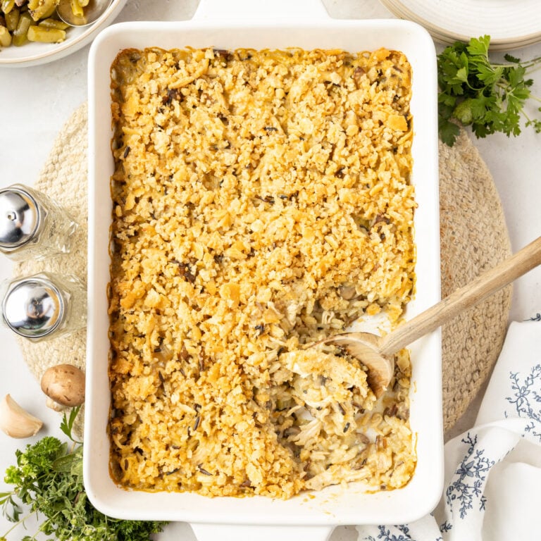 A casserole pan filled with Chicken Wild Rice Casserole and a spoonful taken out of it.