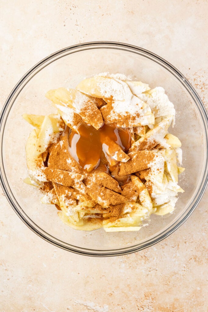 Apple, cinnamon, caramel and flour in a large mixing bowl