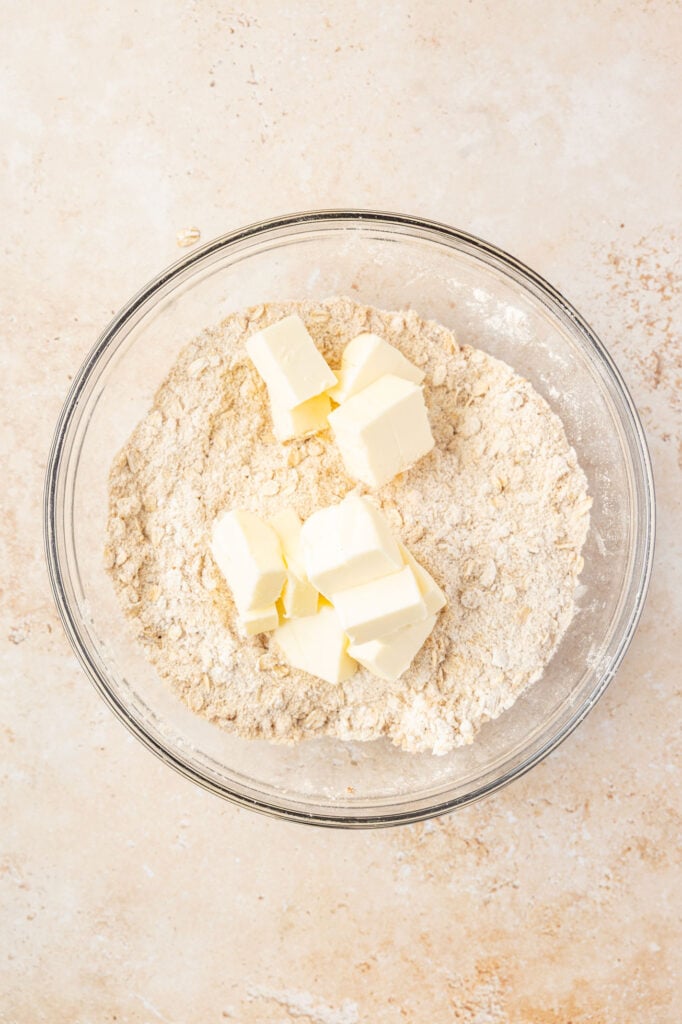 Flour mixture with butter on the top of it in a large mixing bowl.
