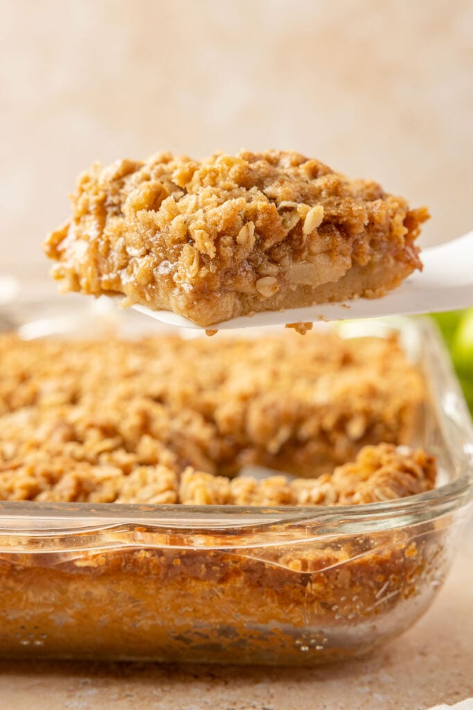 A spatula picking up an apple pie bar out of the 9 x 13 pan