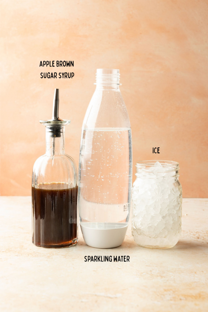 Ingredients for apple soda and containers on a stone surface.