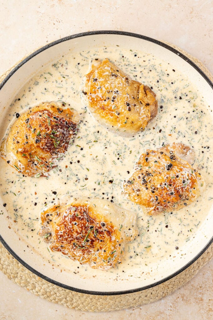 Sear chicken thighs in a skillet in a cream sauce before going in the oven.