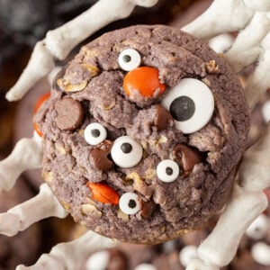 Skeleton holding a Halloween monster cookie in its hand up close