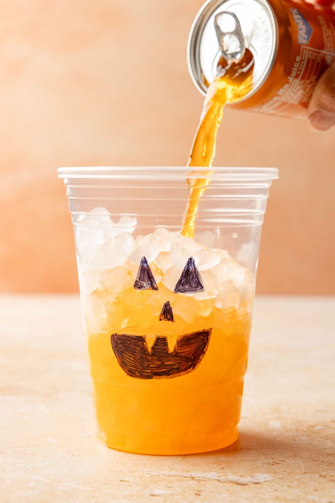 orange soda being poured in the cup.