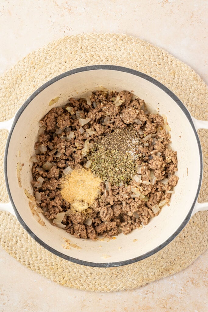 Cooked ground beef and onions in a Dutch oven with spices.