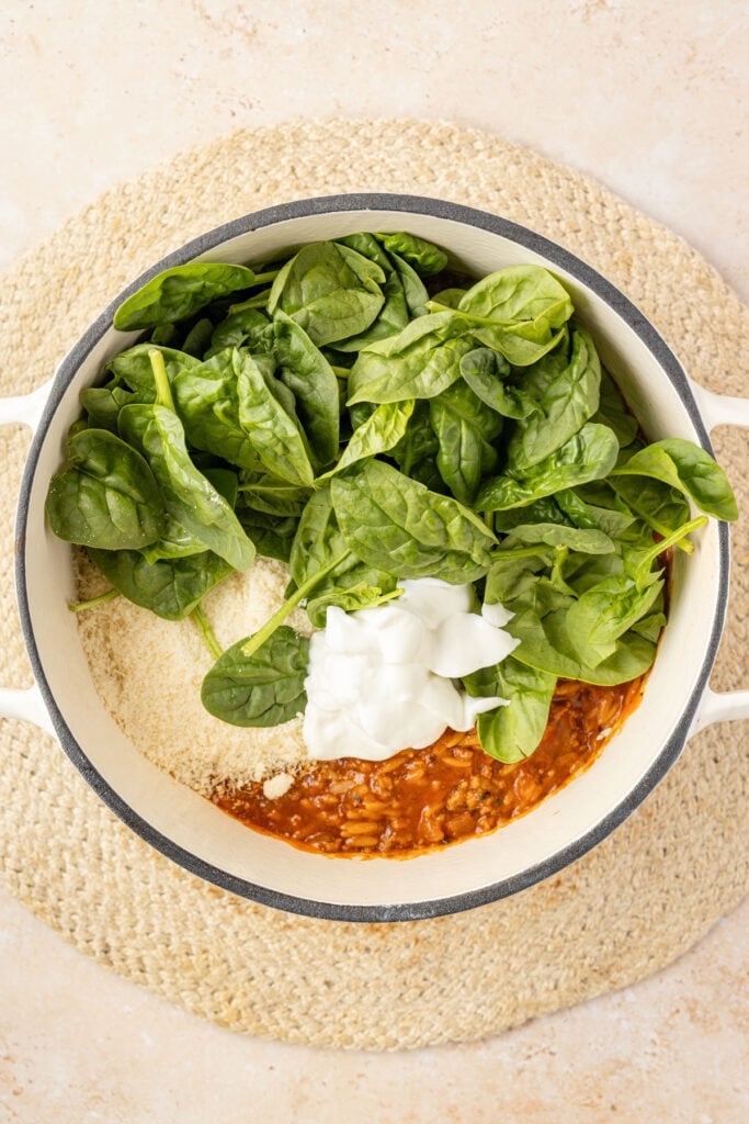 Spinach, Greek yogurt, Parmesan cheese, and beef orzo in a Dutch oven.