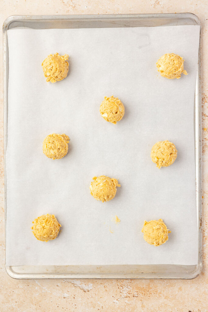 Pumpkin oatmeal cookie dough rolled into balls, placed onto a sheet pan with parchment paper.