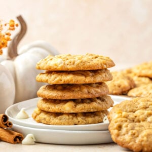 Pumpkin oatmeal cookies on a plate surrounded by more cookies and pumpkins