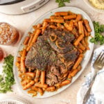 Slow Cooker Chuck Roast plated on a platter with the baby carrots surrounding it.