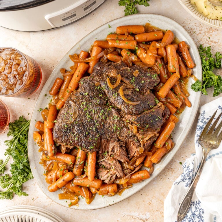 Slow Cooker Chuck Roast plated on a platter with the baby carrots surrounding it.