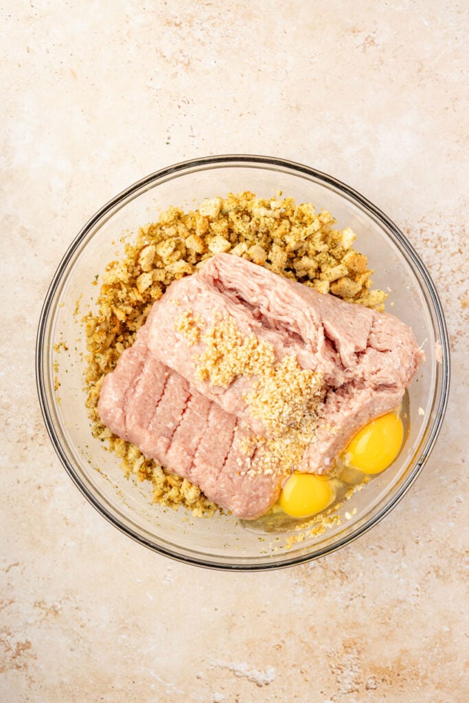 Mixing bowl full of stuffing, ground, turkey, eggs, spices, and garlic